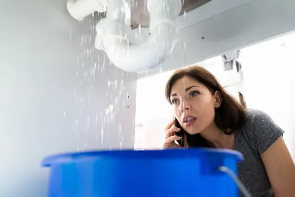 Women Doing Emergency Plumber Phone Call In Kitchen