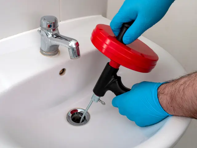 Battle Ground plumber using drain snake to clear clog in Southwest Washington home